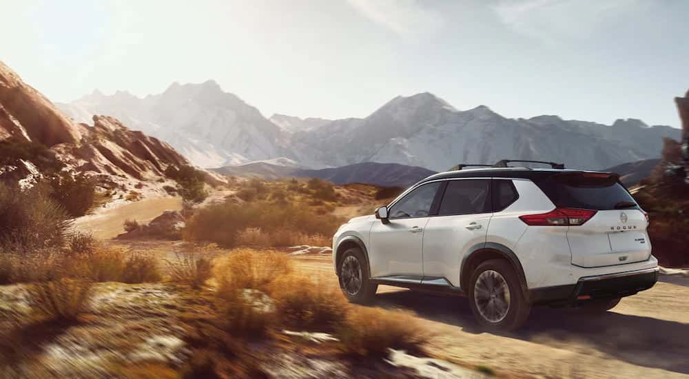 Rear of a white 2026 Nissan Rogue driving off-road.