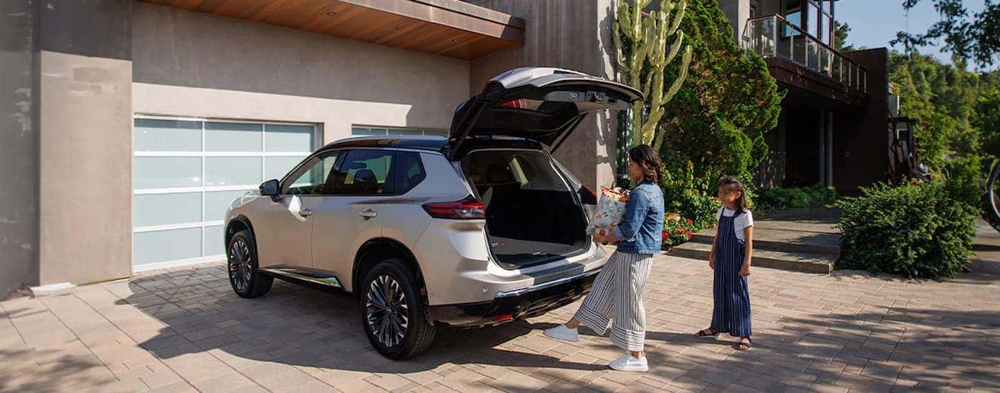 A woman putting things in the rear cargo area of a white 2025 Nissan Rogue