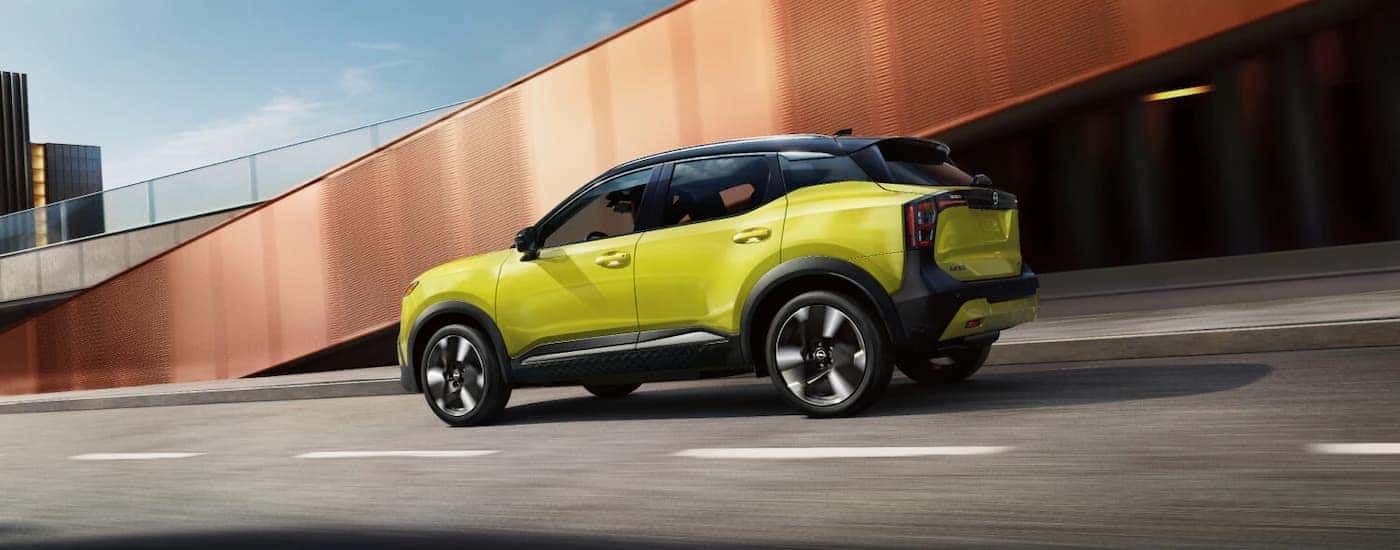 A green 2026 Nissan Kicks driving down a highway