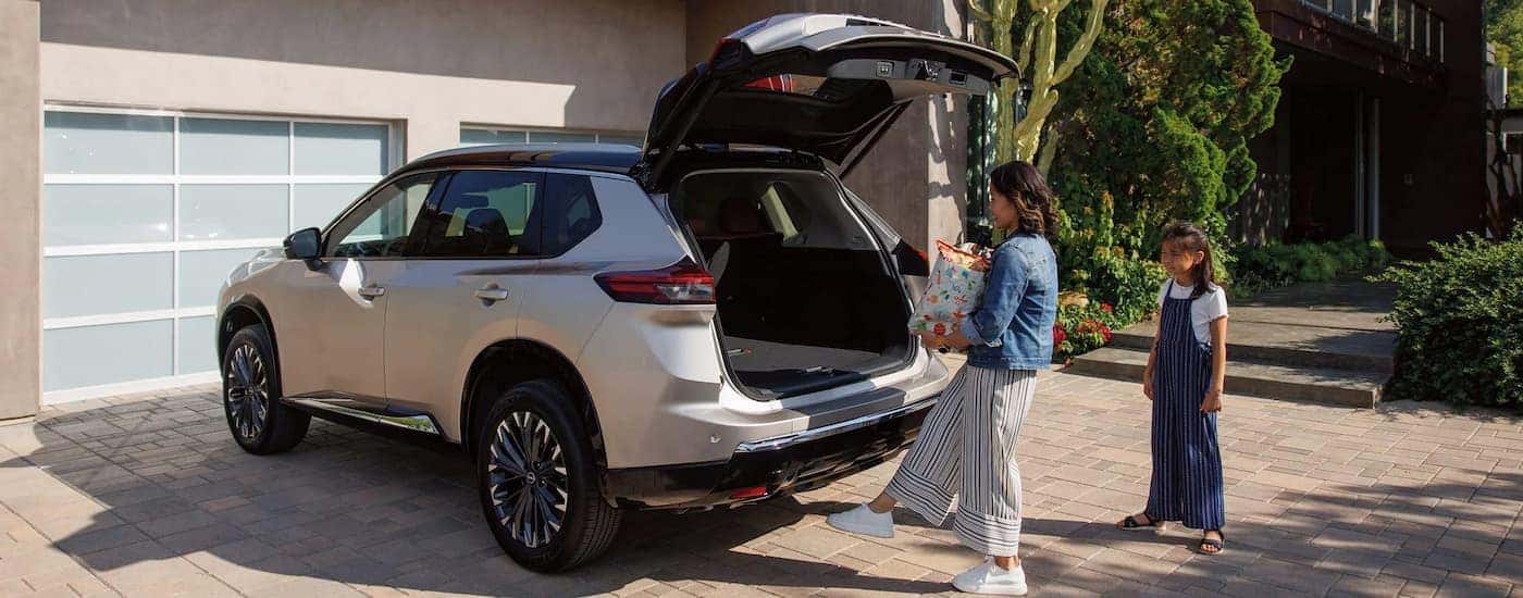 Woman putting a bag into the back of a silver 2026 Nissan Rogue
