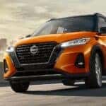 Orange 2023 Nissan Kicks driving away from city.