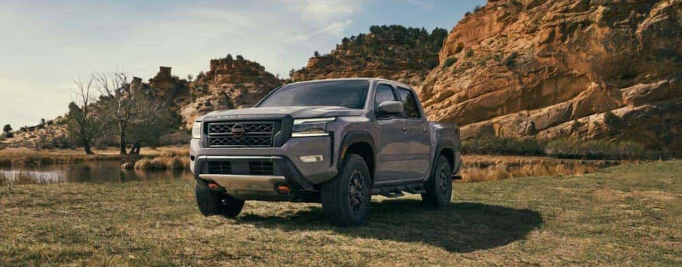 A grey 2022 Nissan Frontier is shown from the front parked in a field.