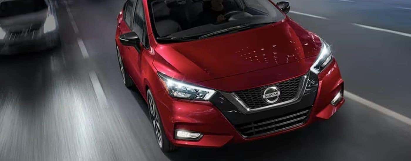 A red 2020 Nissan Versa is shown from the front on a highway.