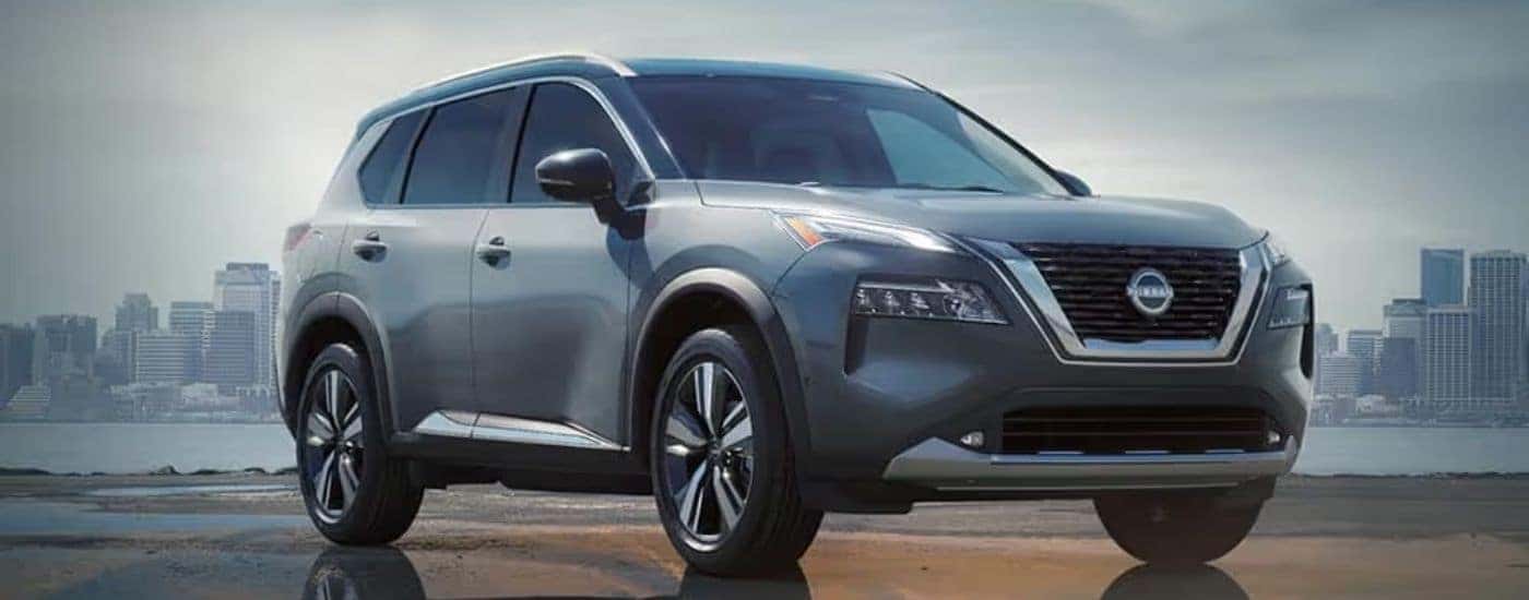 A silver 2024 Nissan Rogue parked in front of a city skyline.
