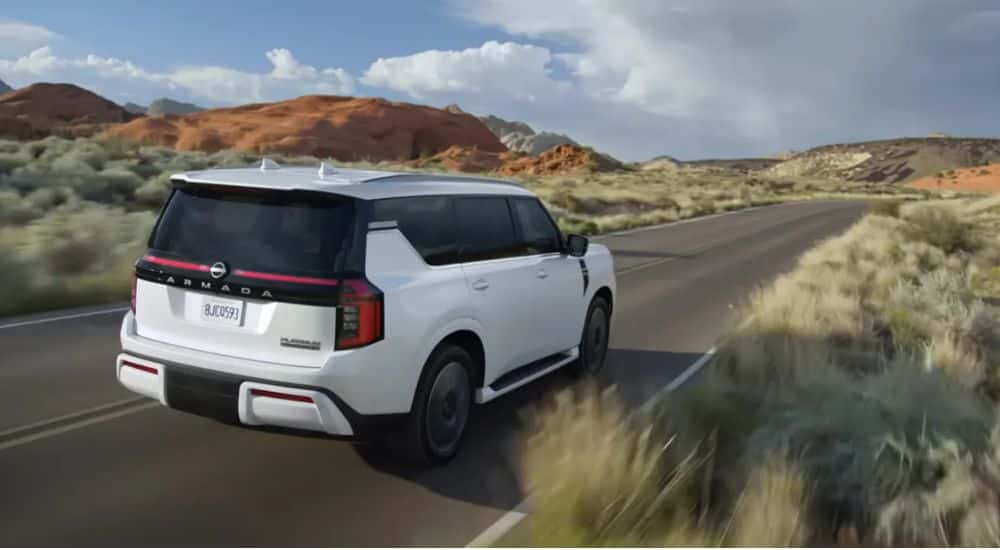 A white 2026 Nissan Armada Platinum Reserve 4WD driving a grass-lined road.