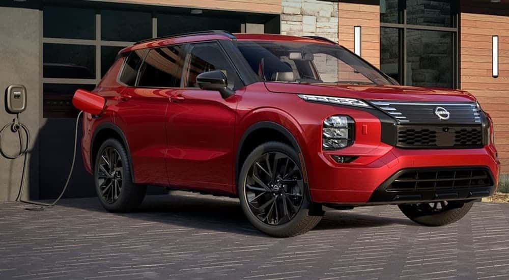 A red 2026 Nissan Rogue Plug-In Hybrid is chrging.