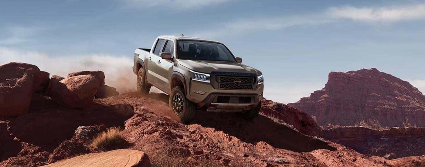A tan 2024 Nissan Frontier off-roading.