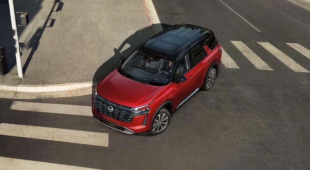 A red 2026 Nissan Pathfinder driving in a city.
