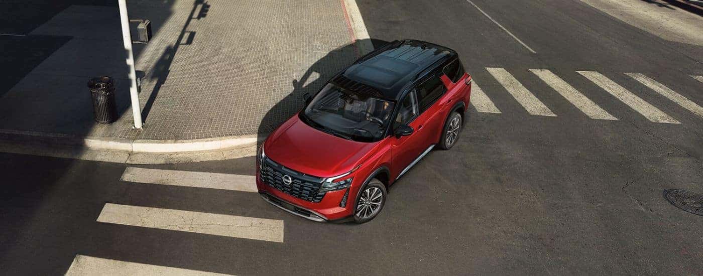 A red 2026 Nissan Pathfinder Platinum turning a corner.