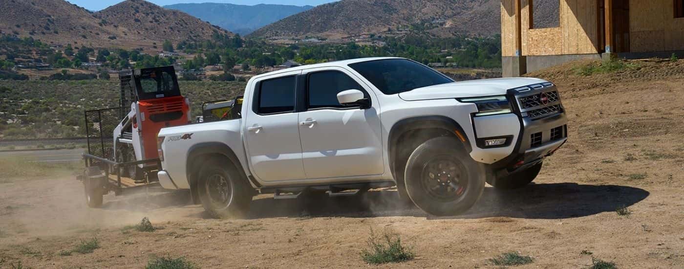 White 2026 Nissan Frontier towing construction equipment.
