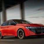 A red 2026 Nissan Sentra driving in a city.