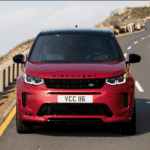 A red Land Rover Discovery Sport driving on a highway.