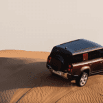 2024 Defender driving over sand dunes in a desert