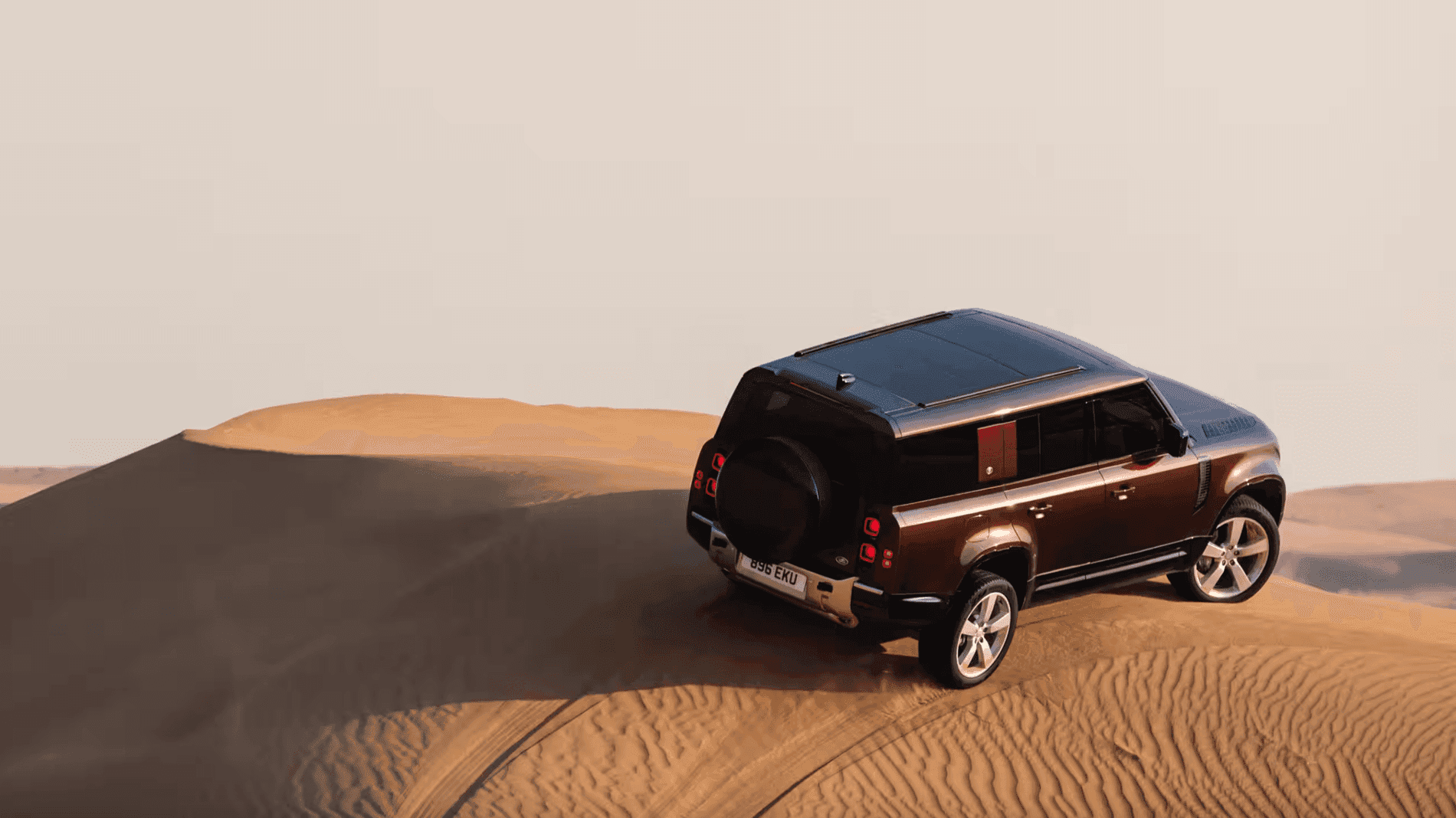 2024 Defender driving over sand dunes in a desert