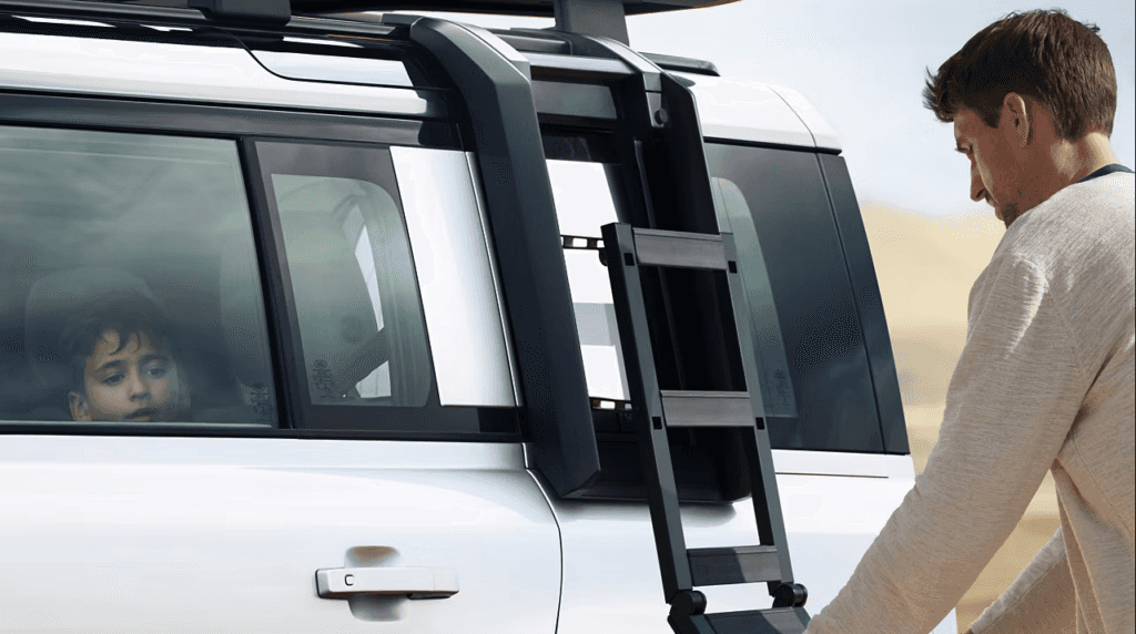 A person using the Defender Fixed Side Steps accessory outside the vehicle