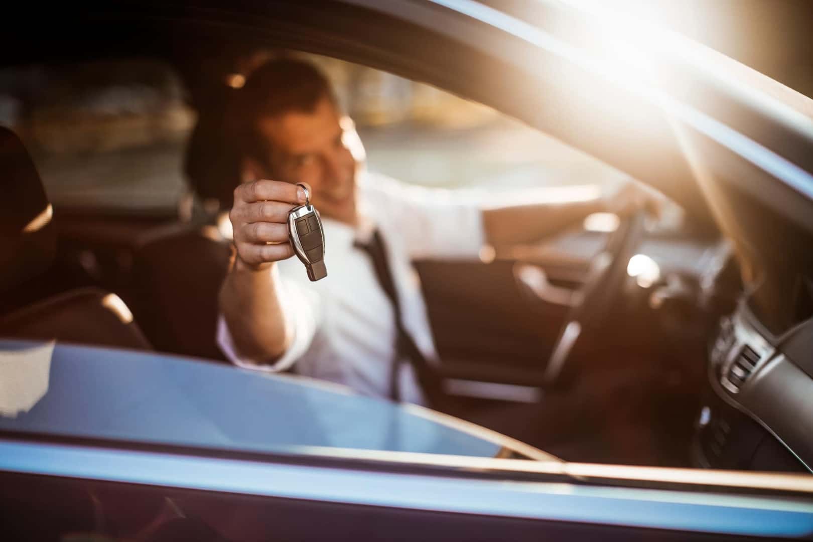 A driver holding up car keys towards the passenger side window
