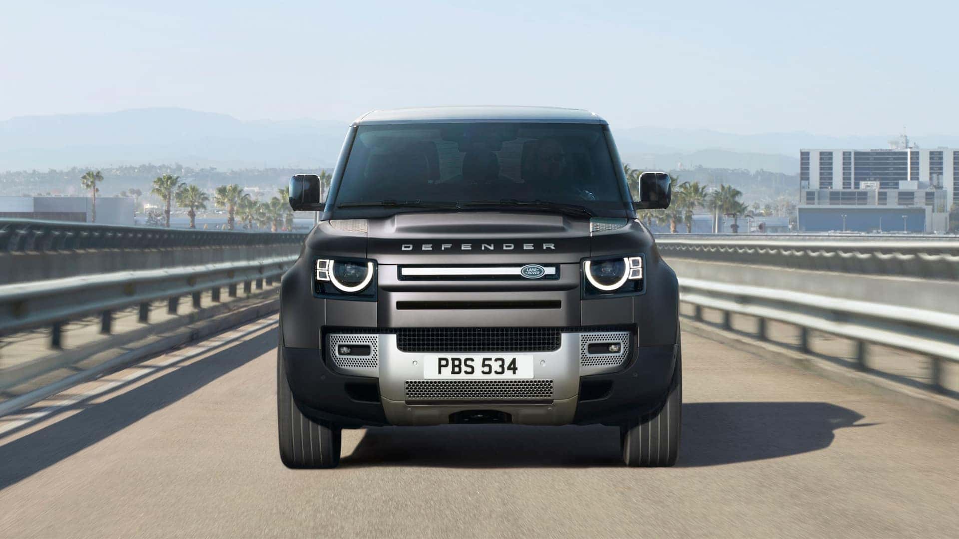 A front view of a black 2025 Defender model vehicle driving along the highway