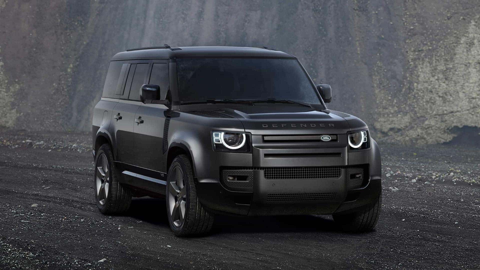 A black 2025 Defender 130 parked on a dirt path.