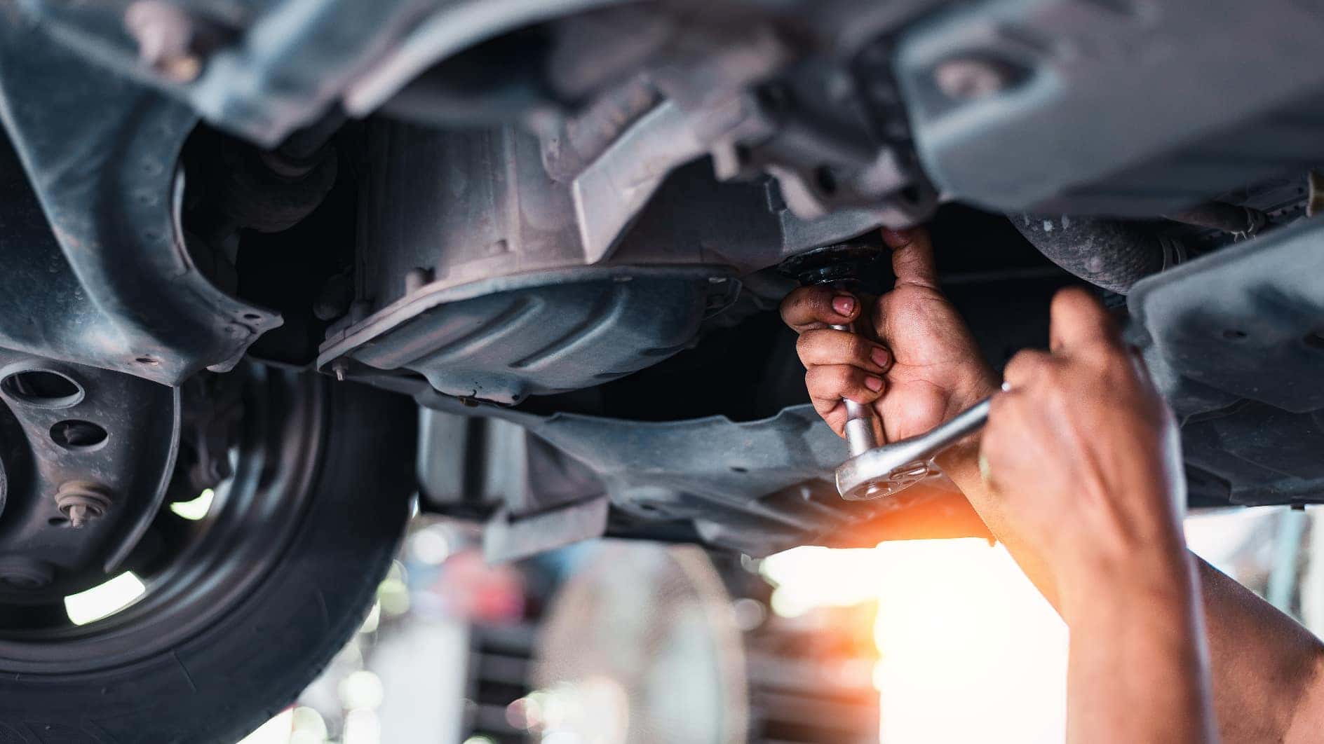 A mechanic performing maintenance on the undercarriage of a vehicle.