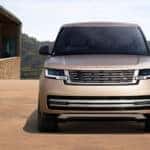 A front view of a light brown 2026 Range Rover parked by a nice house.