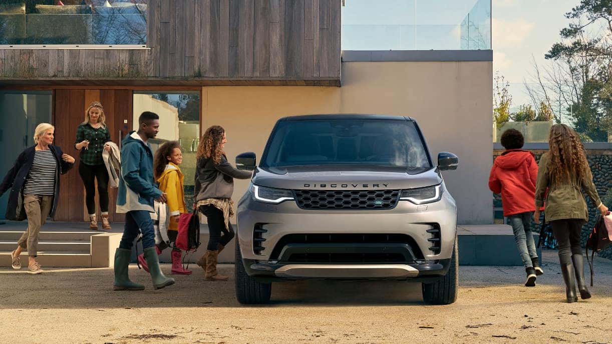 A front view of a gray Discovery, with a large group of people preparing to get into it.
