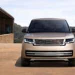 A front view of a beige Range Rover parked outside of a nice house.