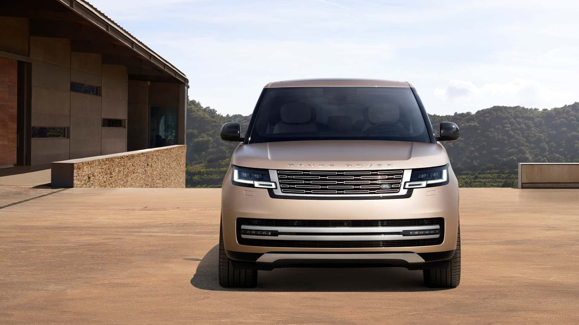 A front view of a beige Range Rover parked outside of a nice house.