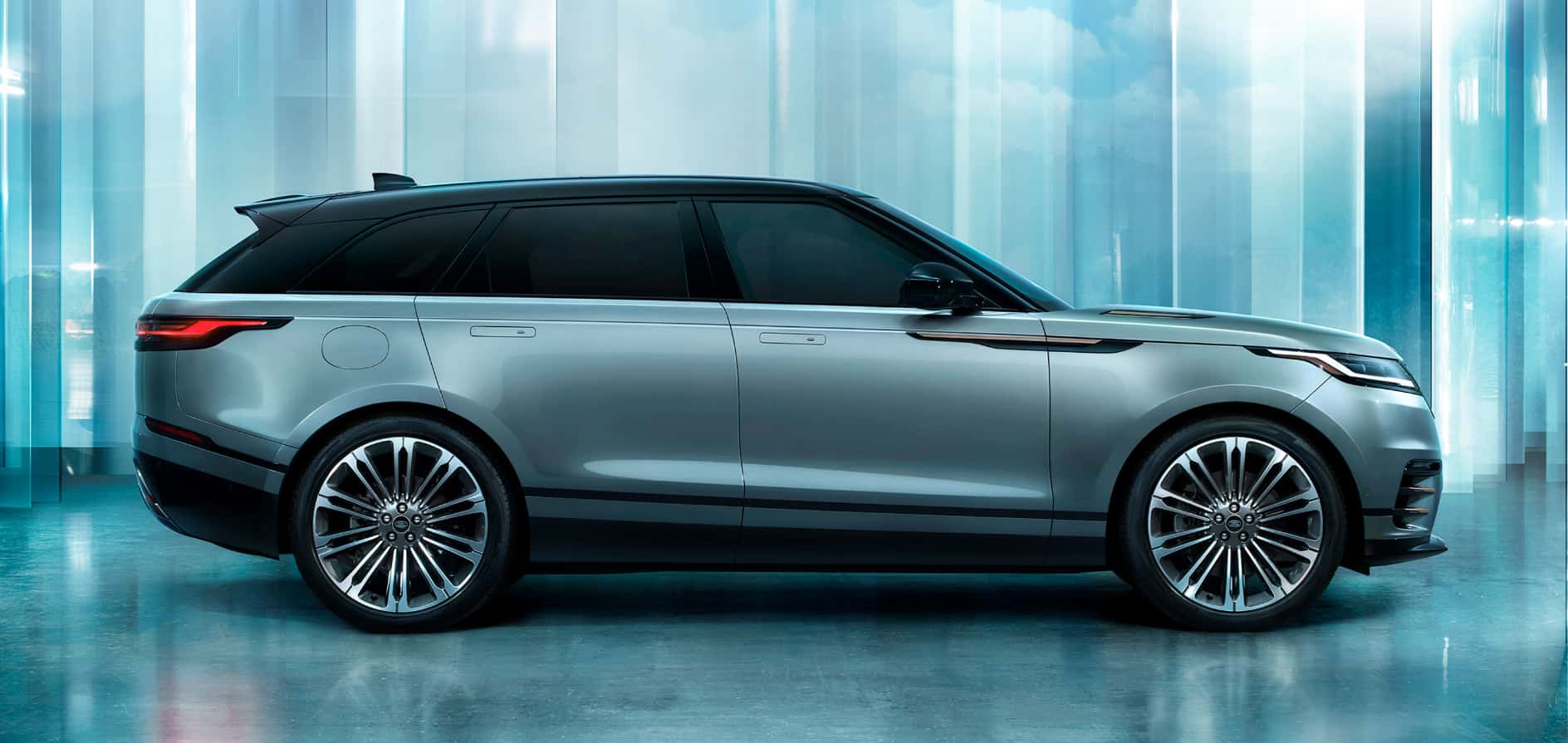 A gray Range Rover Velar in profile in a area that appears to be made from glass.