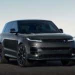 A black Range Rover Sport driving down a winding road in a flat desert.