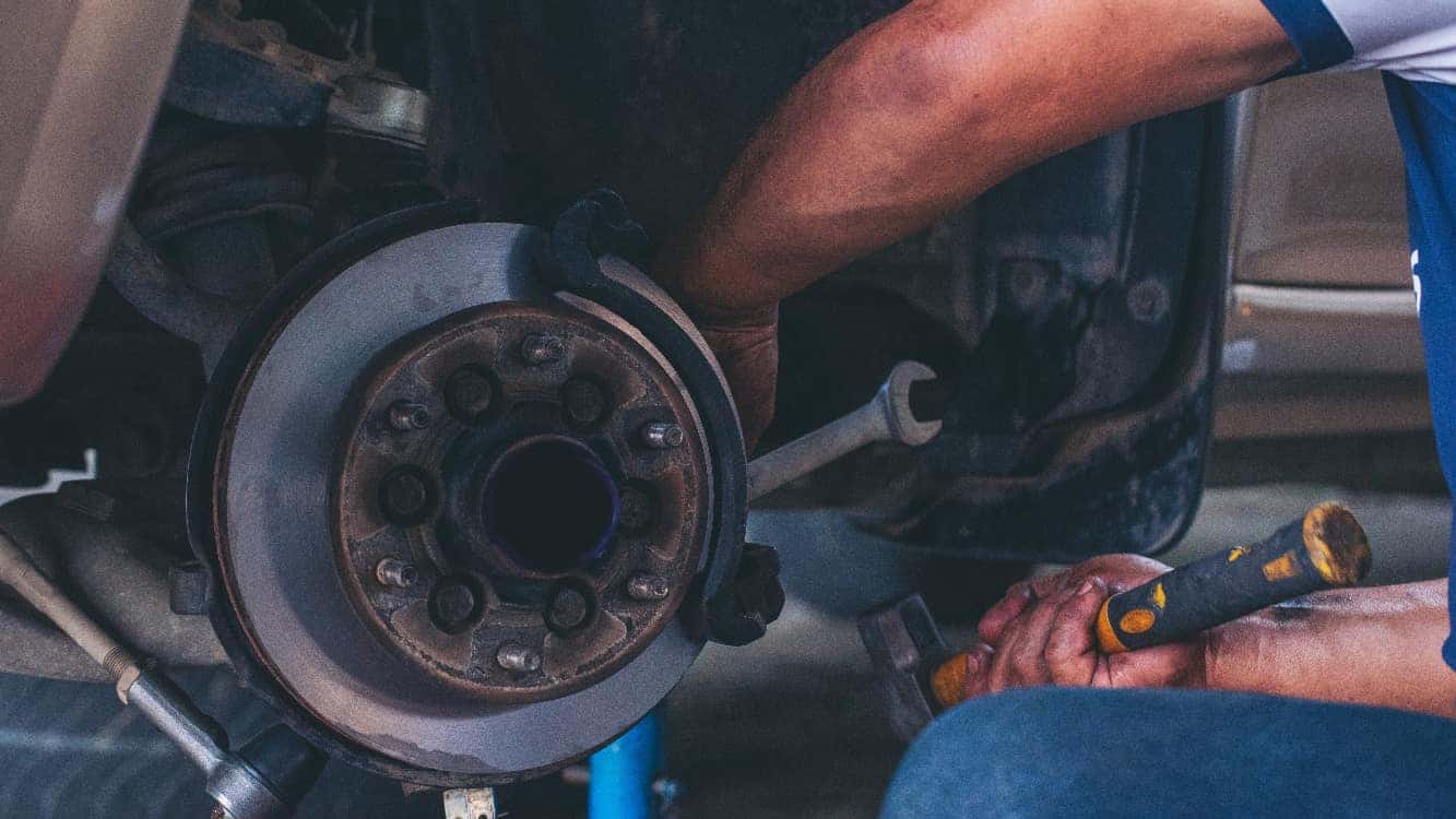 A mechanic performing maintenance on a vehicle's wheel.