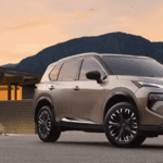 A beige 2024 Nissan Rogue Platinum AWD in front of a home and desert landscape at sunset