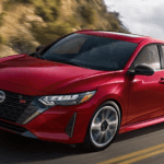 A red 2024 Nissan Sentra driving around a curve on a mountain highway