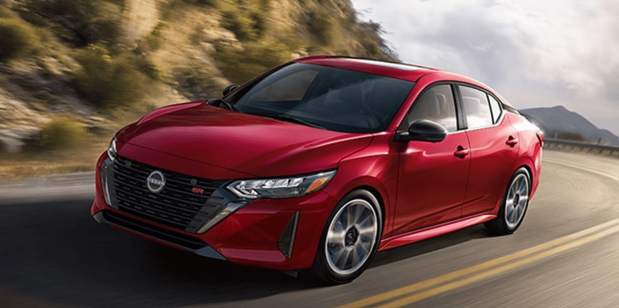 A red 2024 Nissan Sentra driving around a curve on a mountain highway
