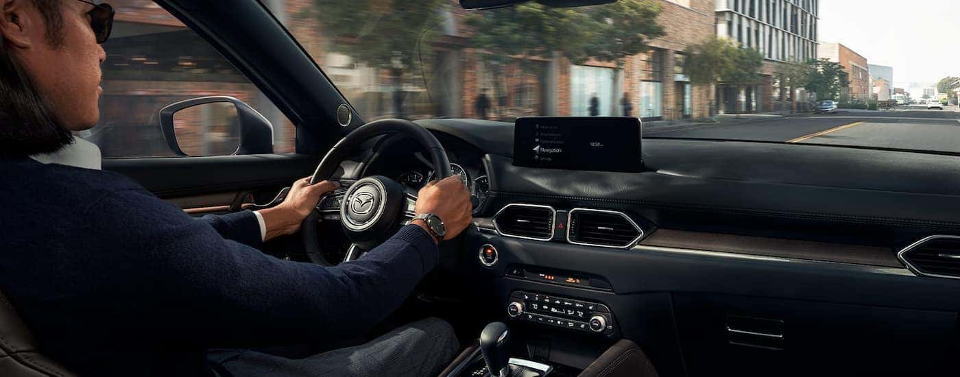 A person is shown driving a 2022 Mazda CX-5 on a city street.