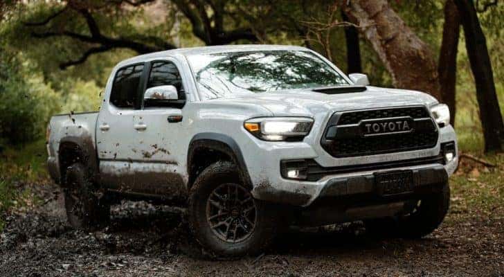 A white 2020 Toyota Tacoma TRD is shown on a muddy path after leaving a used truck dealer.