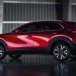 A red 2022 Mazda CX-30 is shown from the side in a dark building.
