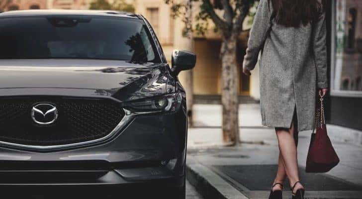 A grey 2021 Mazda CX-5 is shown parked on a city street after leaving a Red Bank Mazda dealer.