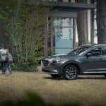 A grey 2022 Mazda CX-9 is shown next to a family after leaving a Red Bank Mazda dealer.