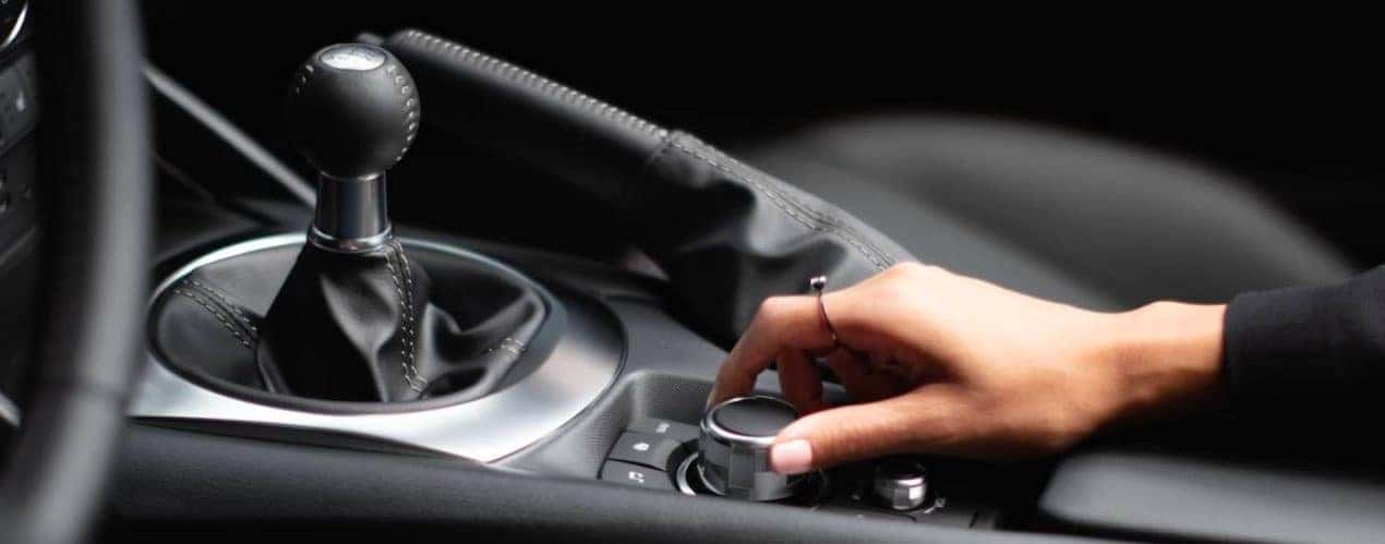 A person is shown turning the infotainment knob in a 2023 Mazda MX-5 Miata RF.