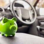 A green piggy bank is shown inside a vehicle.