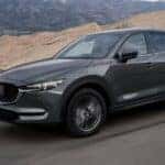 A grey 2020 Mazda CX-5 is shown driving on an open road after a lease buyout.