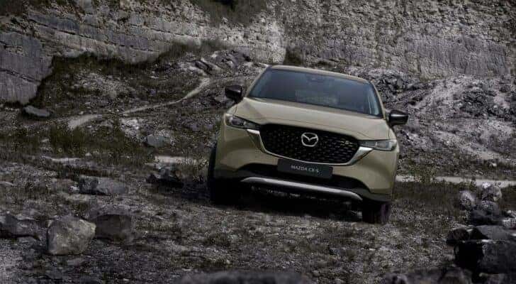 A green 2022 Mazda CX-5 is shown parked in front of rocks after leaving a used Mazda dealer near Chapin, SC.