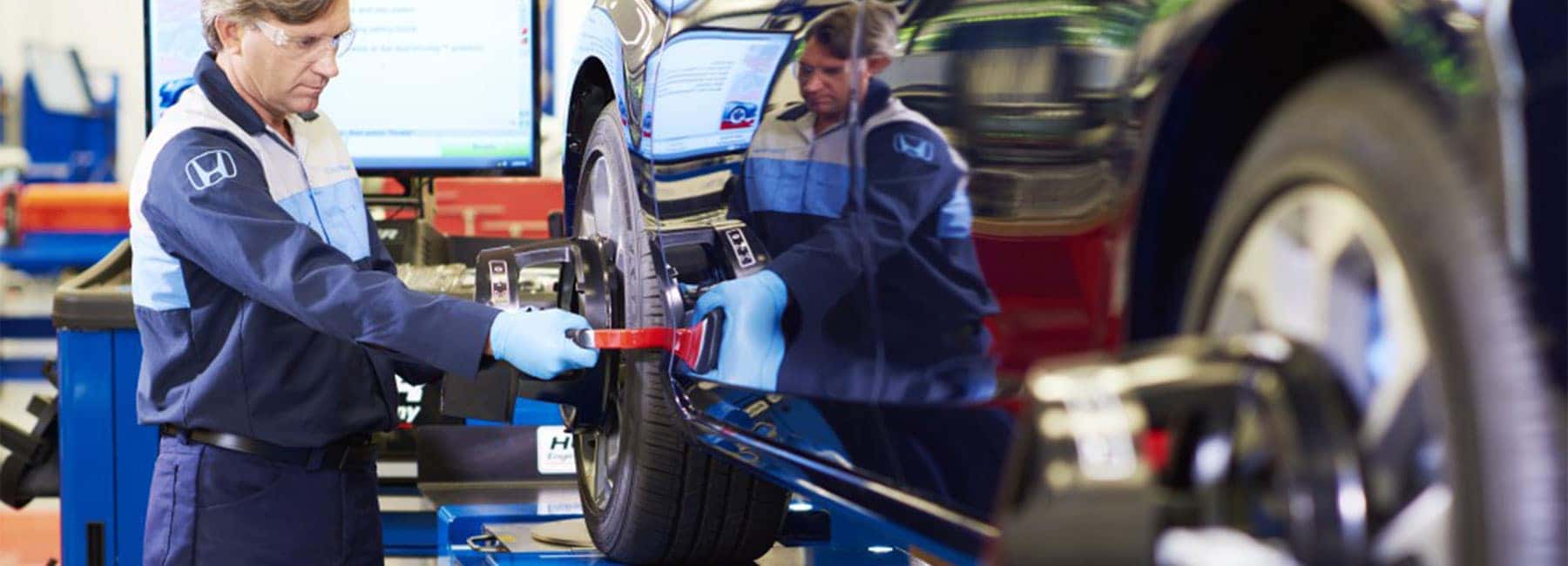 Honda tech performing a wheel alignment.
