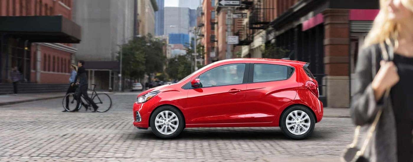 Red 2017 Chevy Spark driving on a city street