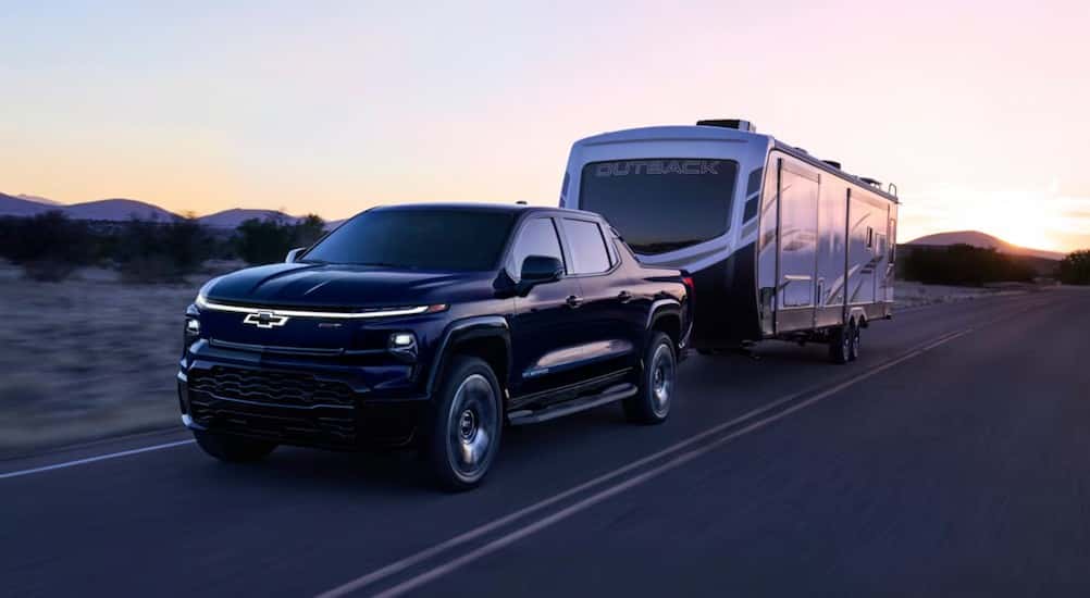 A black 2025 Chevy Silverado EV RST is shown towing a trailer.