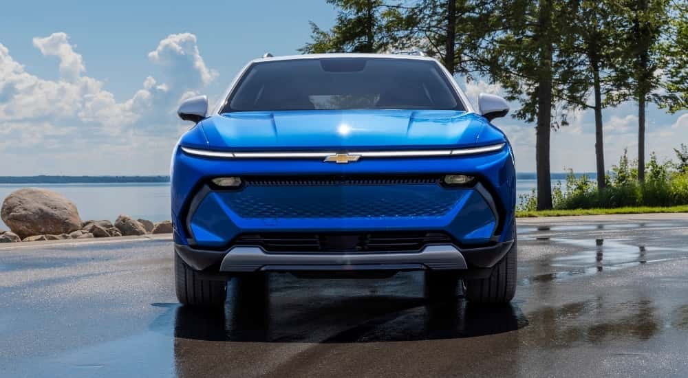 A blue 2024 Chevy Equinox EV 3LT is shown parked on wet pavement.