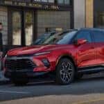 A red 2025 Chevy Blazer RS is parked in front of a shop.