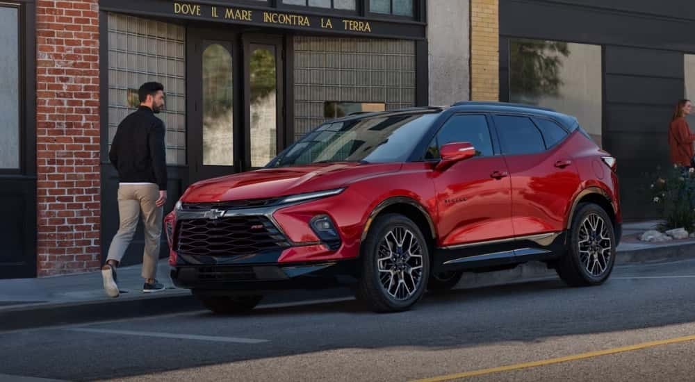 A red 2025 Chevy Blazer RS is parked in front of a shop.