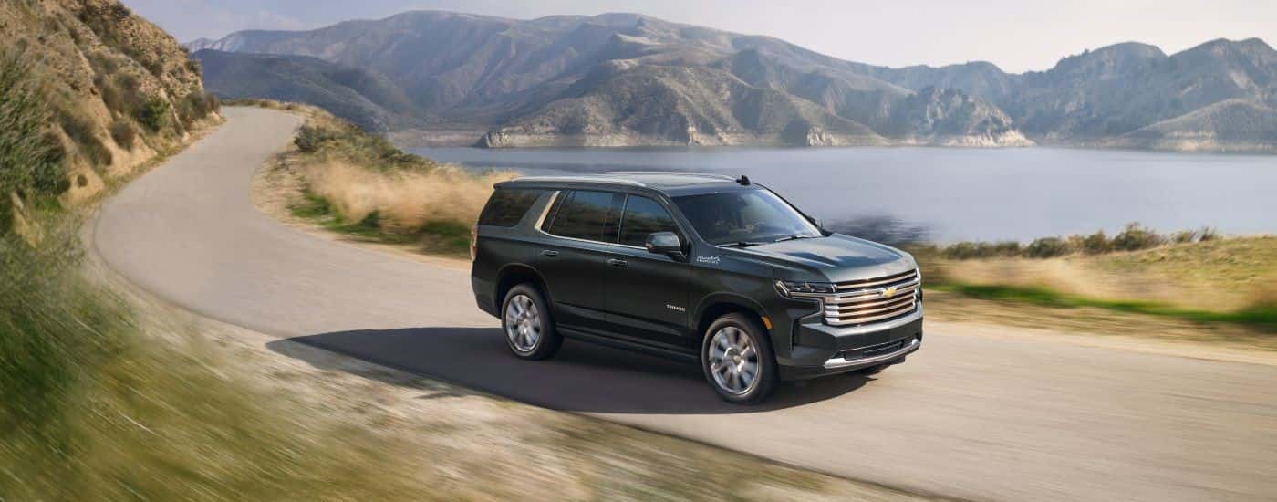 A dark green 2022 Chevy Tahoe High Country driving down a winding road.