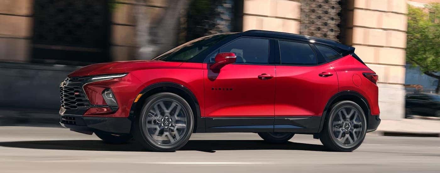 A red 2025 Chevy Blazer RS driving in a city.